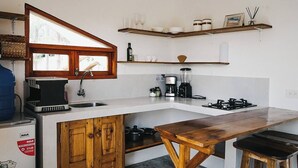 A compact kitchen with a wooden table, a built-in sink, a coffee maker, and a blender.