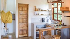 A rustic kitchen with wooden beams, a central island, bar stools, and a window with a view.