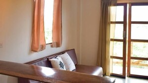 A cozy room with a wooden bench, two stools, a cushioned bench, and a hanging light fixture.