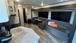 A compact kitchen with a sink, stove, and countertop. - Welcome to All Gussied Up, Glamping at the Gulf. (Port St. Joe)