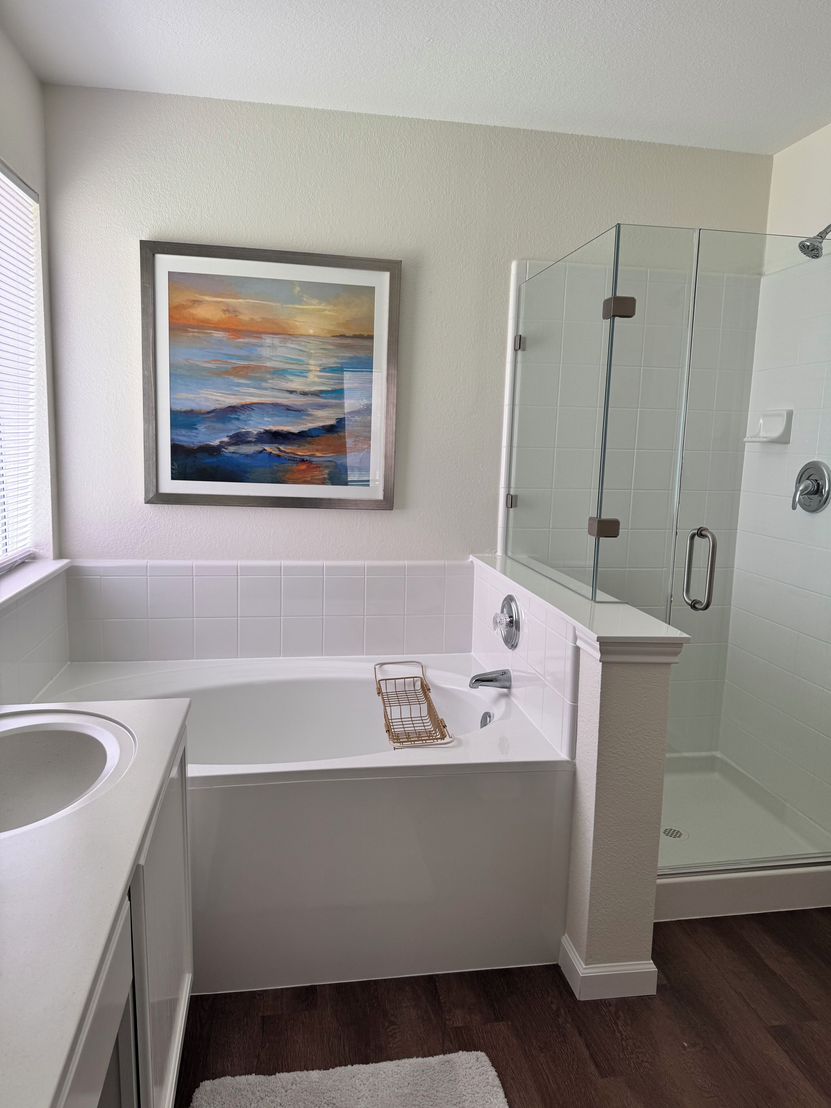 Ein modernes Badezimmer mit Badewanne, Dusche und einem gerahmten Bild an der Wand.