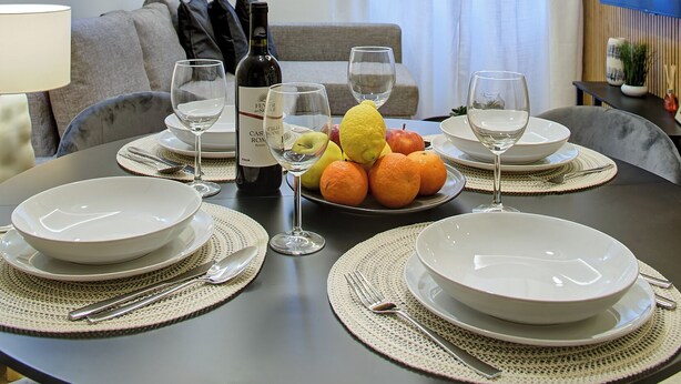 A dining area with a round table set for four, a bottle of wine, and a fruit bowl. - Elegance and comfort in San Giovanni, 3 minutes from metro and ideal for vacation. (Roma)