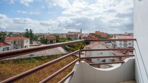 A balcony with a view of a residential area, including houses and a tower.