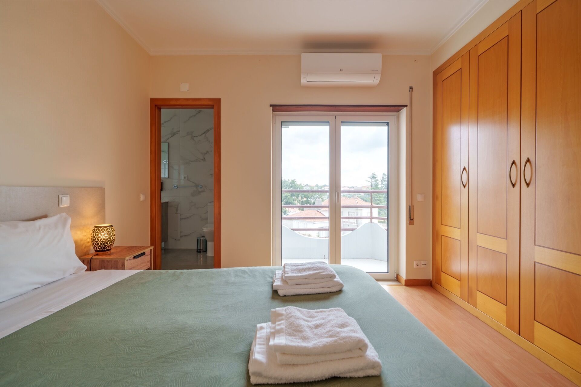 Une chambre à coucher comprenant un lit, une table de chevet et une salle de bain avec douche, donnant sur l’extérieur grâce à une porte coulissante.