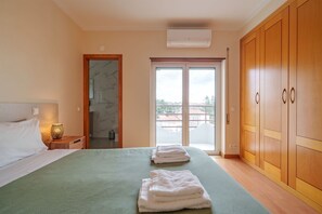 Une chambre à coucher comprenant un lit, une table de chevet et une salle de bain avec douche, donnant sur l’extérieur grâce à une porte coulissante.