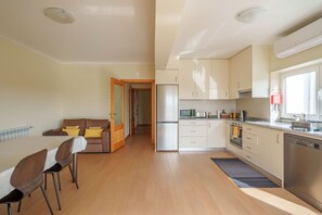 Une cuisine moderne équipée d’un réfrigérateur, d’un four à micro-ondes et d’une cuisinière. On y trouve également un coin repas avec des chaises et une table.