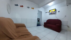 A living room with a brown sofa, a red sofa, and a television mounted on the wall. - Cabo frio white sand / house 02 (Jardim Caiçara Cabo Frio)