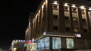 A multi-story hotel with illuminated signage and a well-lit entrance. - AlShowaish Apartments (Taif)