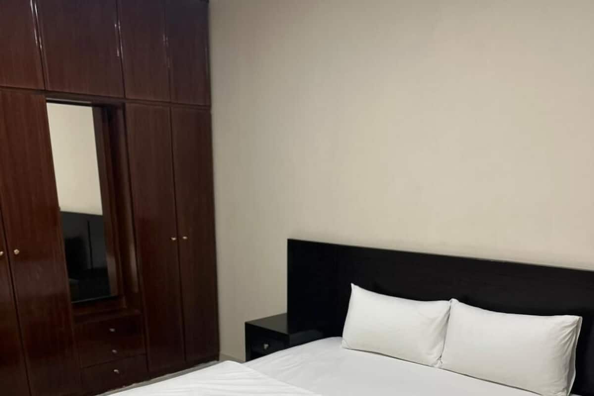 A bedroom with a large bed, a wardrobe, and a nightstand.