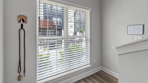 A room with a large window with blinds, a wall-mounted light switch, and a framed picture with text. - #StokeHotel: Boho Outdoorsy Vibes, Paddleboards, Kayak, Dog Park (Chattanooga)