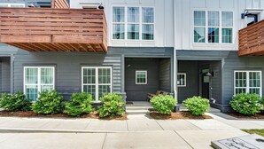 A two-story residential building with a front porch, multiple windows, and a small garden area with shrubs. - #StokeHotel: Boho Outdoorsy Vibes, Paddleboards, Kayak, Dog Park (Chattanooga)
