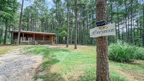 Een chalet met de naam 'Honeymoon' in een bebost gebied, met een grindpad ernaartoe.