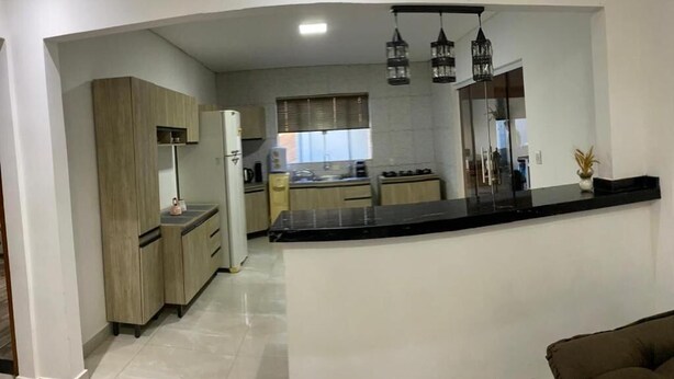 Una cocina moderna con una isla curva, armarios de madera e iluminación colgante.