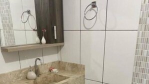 Un baño con un lavamanos color beige, un espejo, un inodoro y un perchero para toallas.