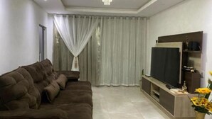 Una sala de estar moderna con un sofá marrón, un televisor de pantalla plana y un florero decorativo.
