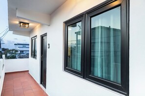 A corridor with a tiled floor, a door with a number, and large windows with curtains. - Modern San Juan Apt w/ Parking Near Ocean Park (San Juan)