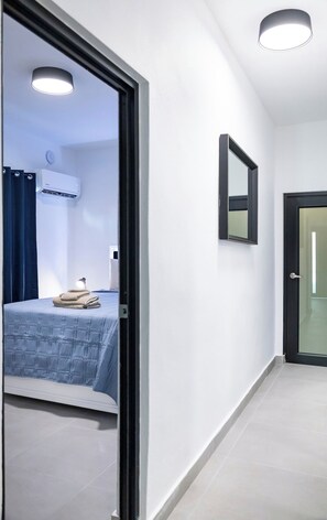 Een gang met een bed, een spiegel en een airconditioner.
