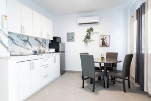 A modern kitchen with white cabinets, a marble backsplash, and a dining area with a round table and four chairs. - Modern San Juan Apt w/ Parking Near Ocean Park (San Juan)