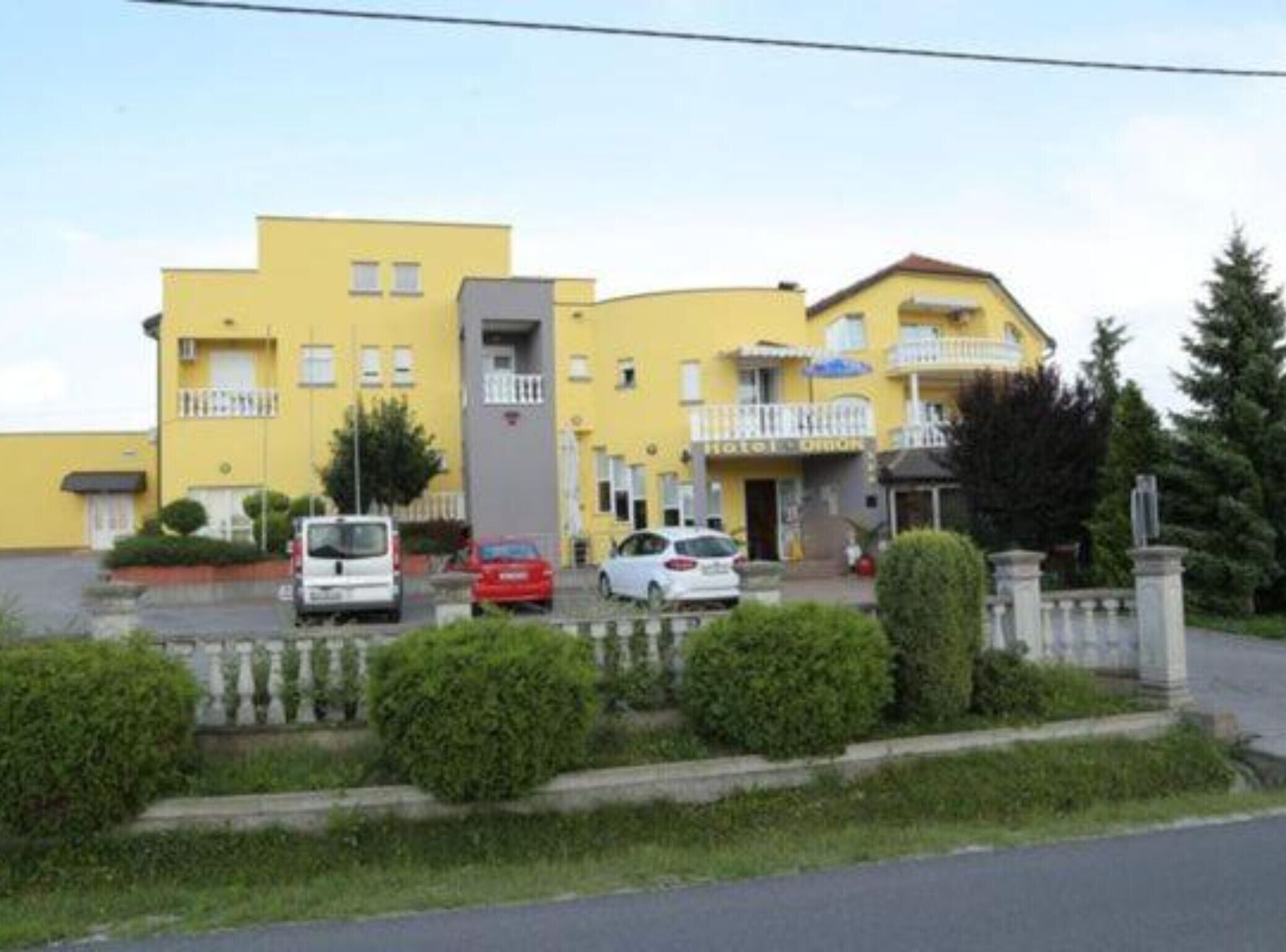 A yellow building with multiple balconies and a parking area with several cars.