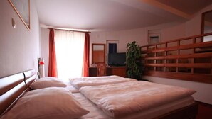 A hotel room with two beds, a TV, a desk, and a plant. - Hotel Orion - Double Room with Mountain View 4 (Ivanec)