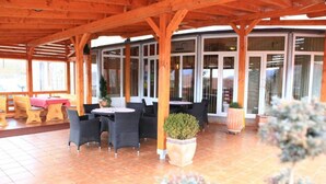 An outdoor patio with wooden beams, round tables, and chairs. - Hotel Orion - Double Room with Balcony 1 (Ivanec)