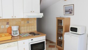 A compact kitchen with white cabinets, a coffee maker, a microwave, and a small oven.