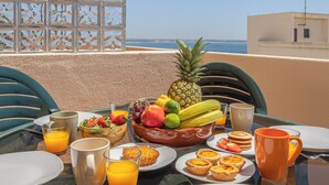 A breakfast table with fruit, pastries, and orange juice on a balcony overlooking the sea. - Huniky 35 - Sea view, Wifi and air conditioning (Lagos)