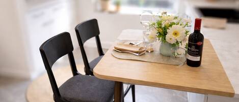 A dining table with a vase of flowers, a bottle of wine, and a folded napkin.