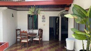 A patio with a table and chairs, potted plants, and a white bucket.