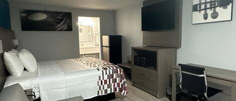 Une chambre à coucher avec un lit, un bureau, une chaise, une télévision et une porte.
