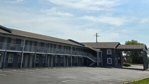 Un motel con estacionamiento, un acceso cubierto y una escalera que lleva a la entrada.