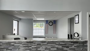 Una zona de recepción con un mostrador de piedra, un reloj y banderas de Estados Unidos.