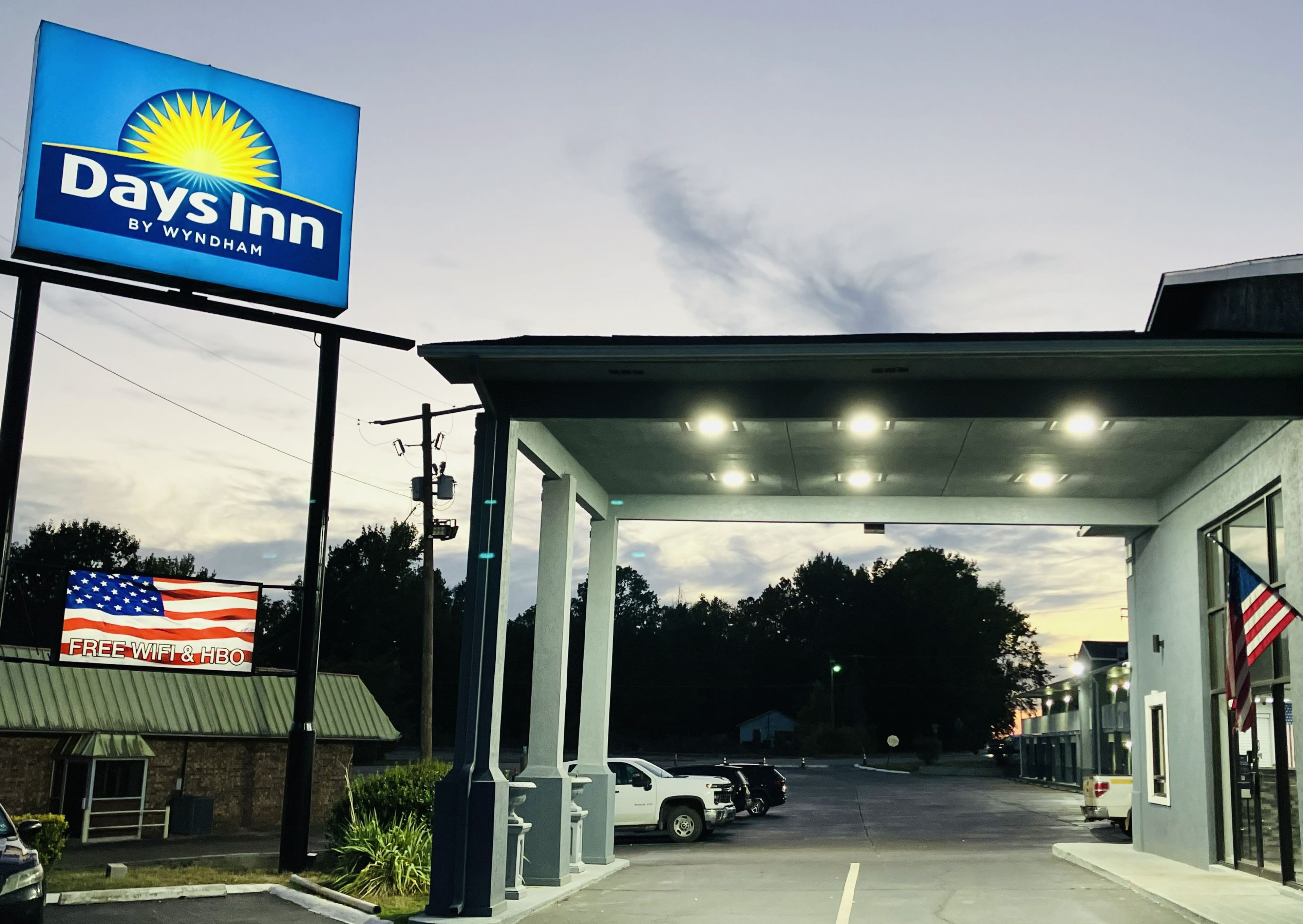 A Days Inn by Wyndham with a clear sky, a gas station canopy, and an American flag.