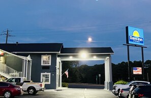 A Days Inn by Wyndham with a parking lot, a flag, and a clear sky. - Days Inn by Wyndham Camden AR (Camden)