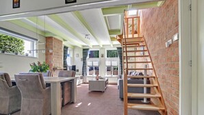 A modern interior with a kitchen, dining area, and a staircase against a brick wall. - Vacation home near the beach and the cities of Amsterdam and Haarlem. (Beverwijk)