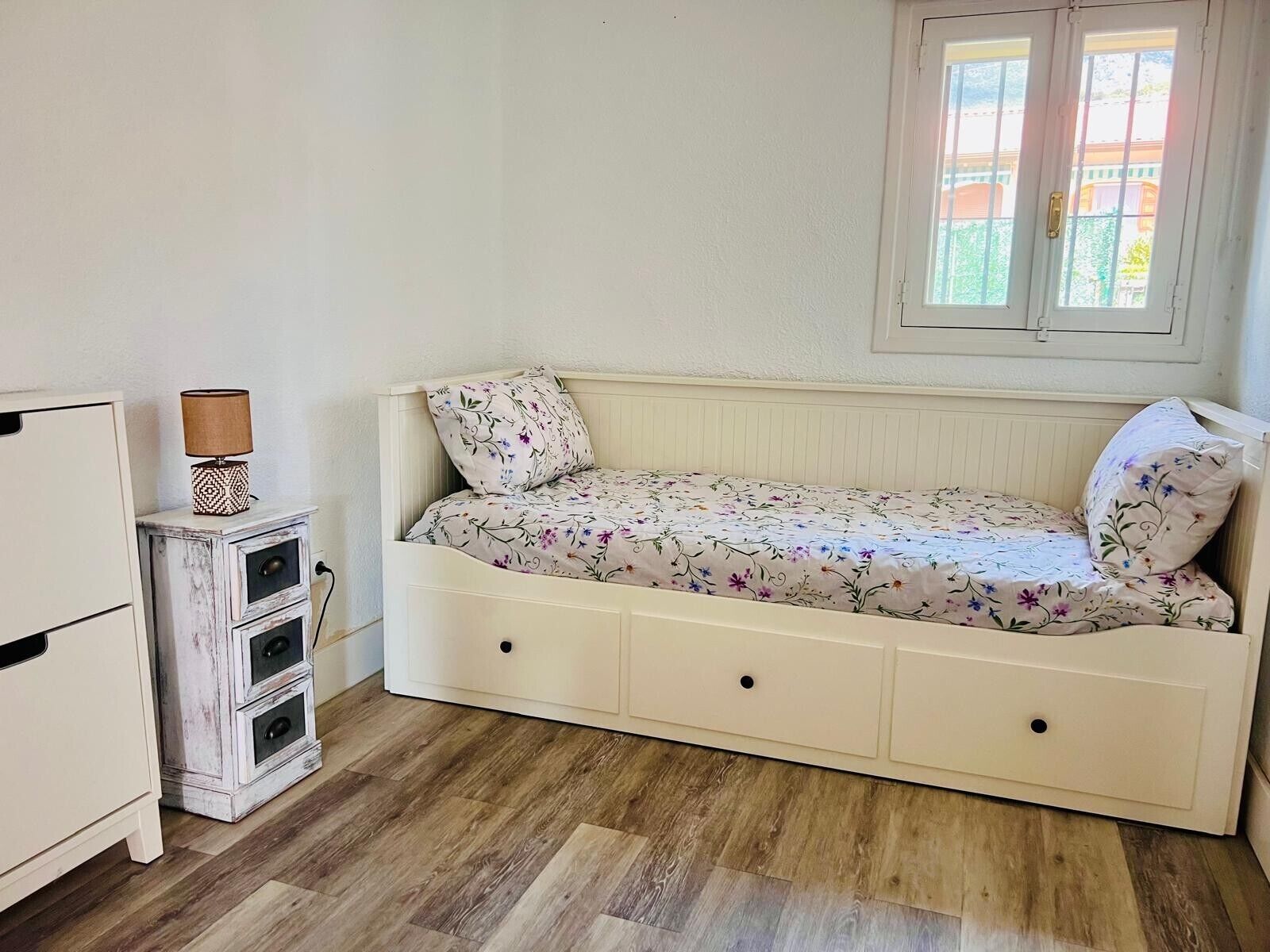 A bedroom with a bed, a dresser, a lamp, and a window.