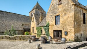 Un edificio de piedra con una torre, barriles y un cartel que indica un lugar histórico.