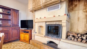 Una chimenea con un televisor, armarios de madera y piso de baldosas.