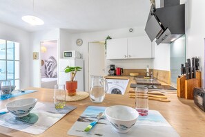 Moderni keittiö, jossa on valkoiset kaapit, mikroaaltouuni, kahvinkeitin ja pesuallas.