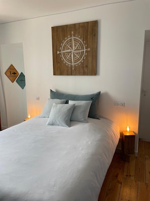 A bedroom with a bed, pillows, a wall-mounted compass artwork, and two bedside lamps.