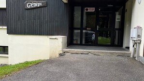Une entrée d’immeuble avec une enseigne indiquant « Genepi », une façade en noir et blanc et une porte bien visible.