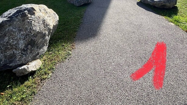 Un bâtiment moderne doté d’un toit plat, d’un balcon et d’un chemin de gravier menant à l’entrée.
