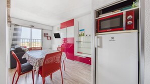 Eine kompakte Küche mit Mikrowelle, Kühlschrank und Essbereich mit Tisch und Stühlen.