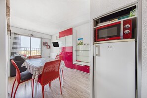 A compact kitchen with a microwave, refrigerator, and dining area with a table and chairs.