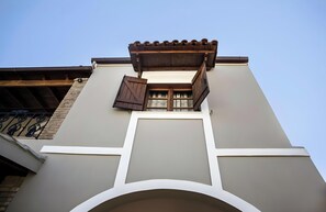A building with a balcony, a window with shutters, and a tiled roof.
