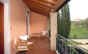 A balcony with wooden chairs, a small table, and a view of a green landscape. - Apartment 'Corfu Club Junior Suite' with Shared Pool, Wi-Fi and Air Conditioning (Corfu)