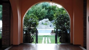 Une entrée en arc de cercle offrant une vue sur une fontaine et de la verdure.