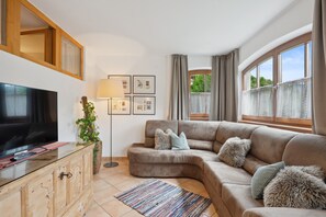 A living room with a television, sofa, and a plant.
