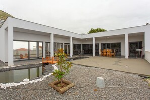 A modern building with a covered outdoor area, a small pond, and outdoor furniture. - Studio 'Mariana' with Atlantic View, Culinary Experience and Unique Hospitality (Gaula)