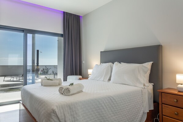 A hotel room with a large bed, two bedside tables, a view through a glass door, and a balcony.